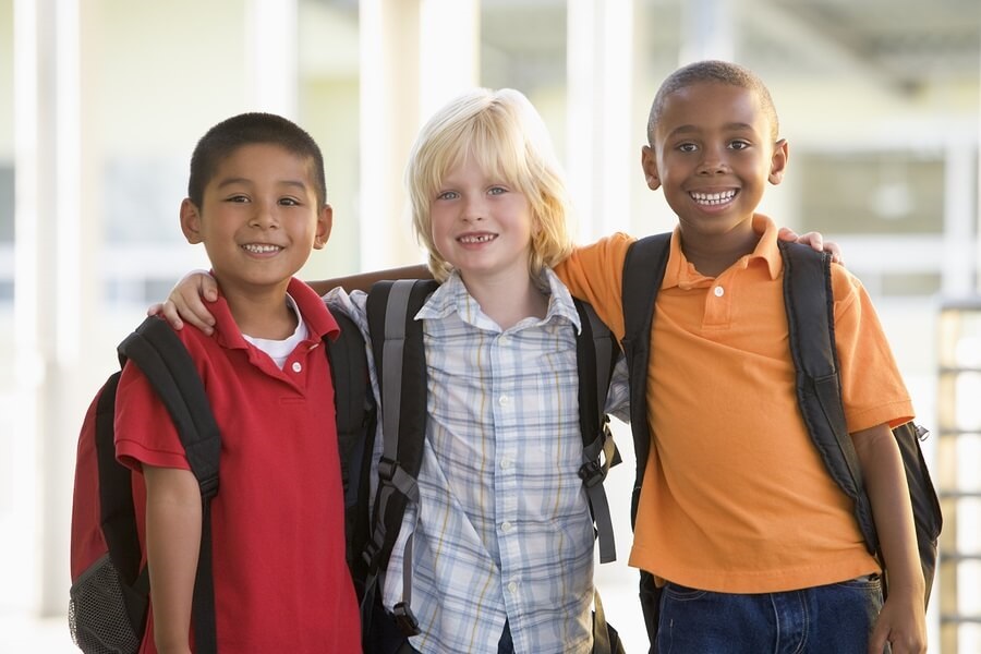 Three boys with backpacks smiling