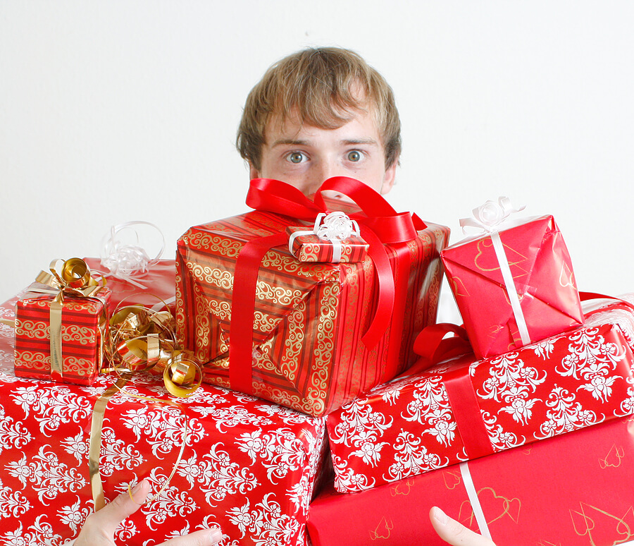 man peeking over tall stack of presents