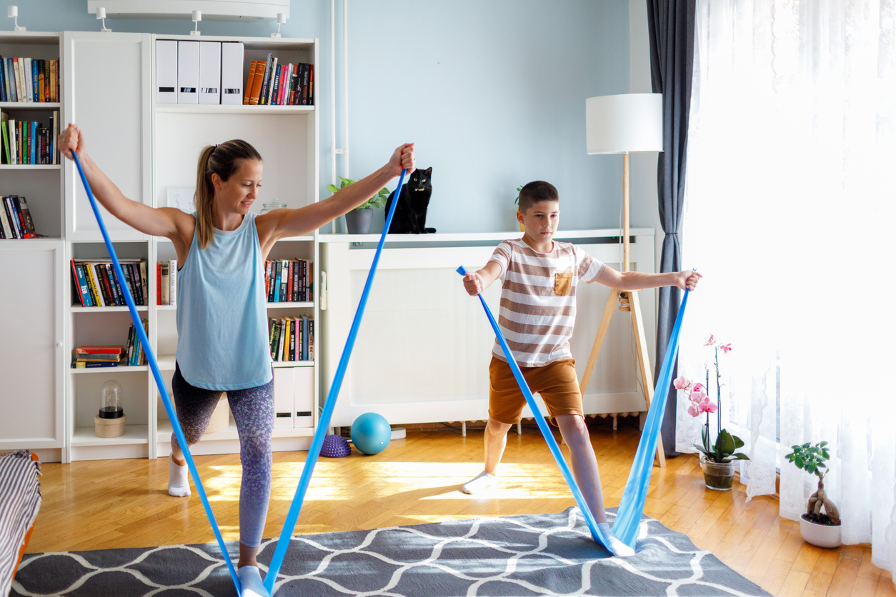 Mother and 12 year old son exercising with elastic bands. Mother helping son to exercise correct.