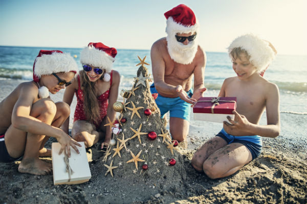 family exchanging gifts on vacation at beach