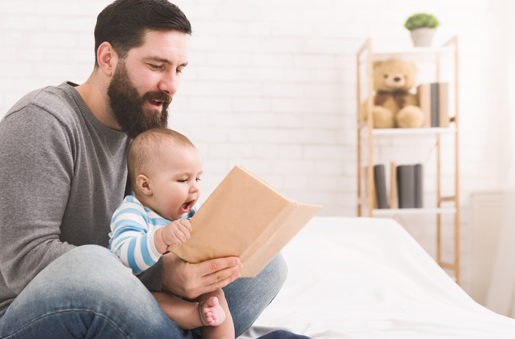 Dad bonding with newborn by reading to baby 