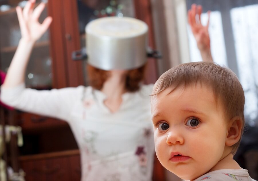 Alarmed child with crazy mom with pot on head in background