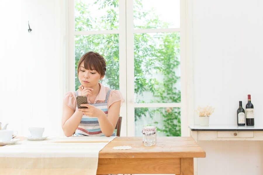 Asian woman sitting in kitchen on phone