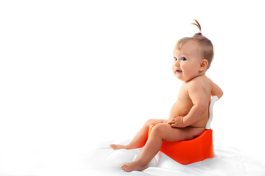 Baby on toilet against white backdrop