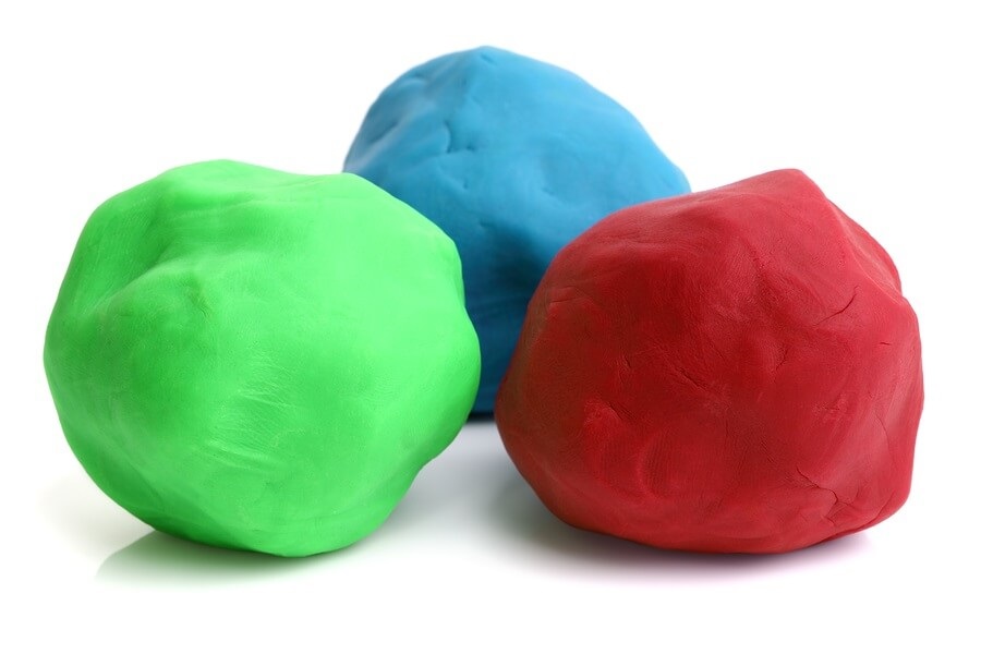Three colorful balls on clay on white background