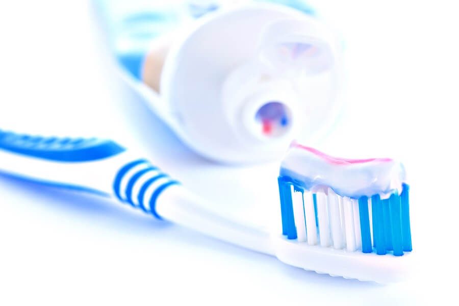 Close up of blue toothbrush and tube of toothpaste