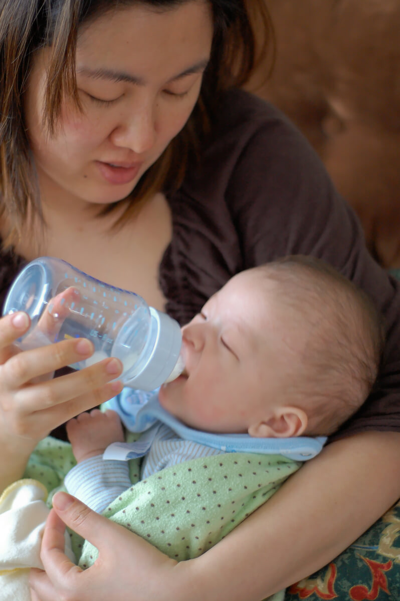 Mother bottle feeding child