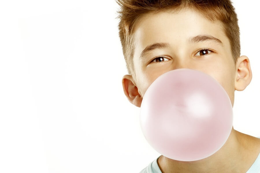 Boy blowing bubble of gum against white background