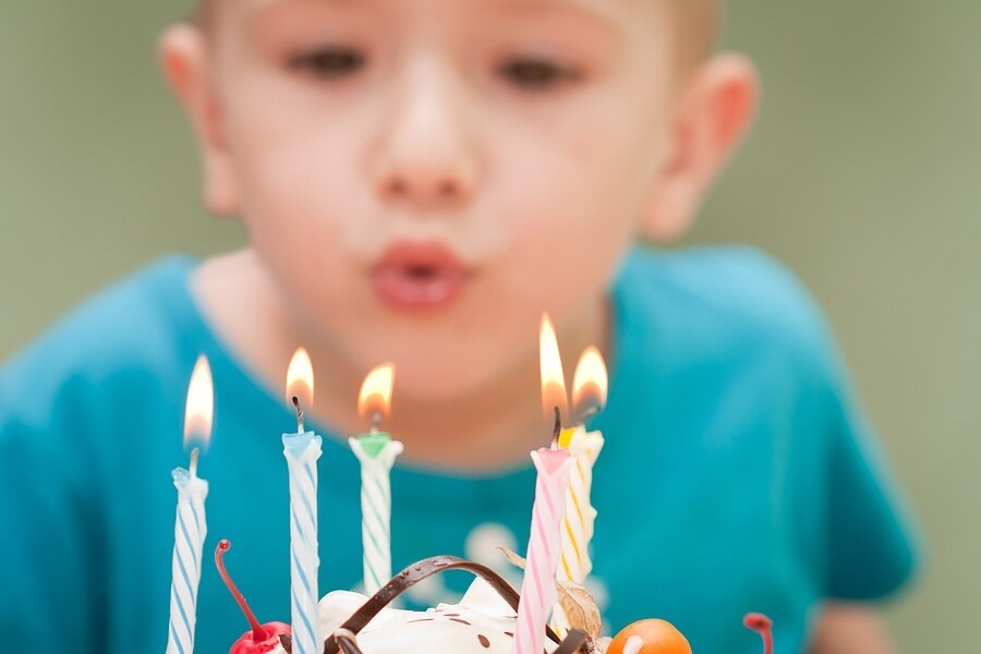 Close up of cake with boy blowing out candles