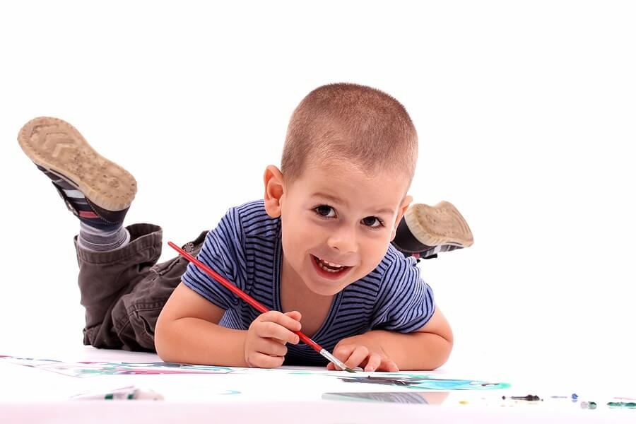 Young boy finger painting against white backdrop