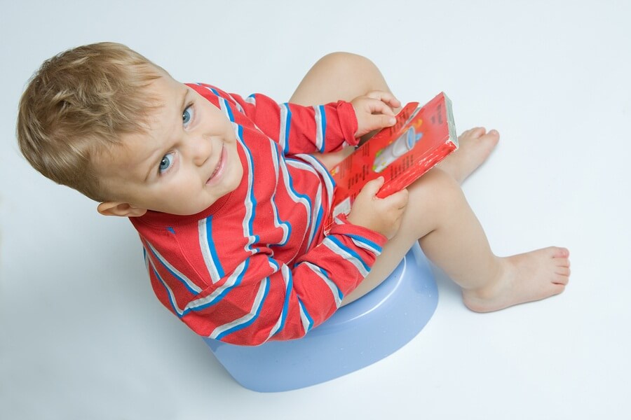 Young boy reading on training toilet