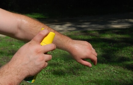 Man applying bug spray to arm