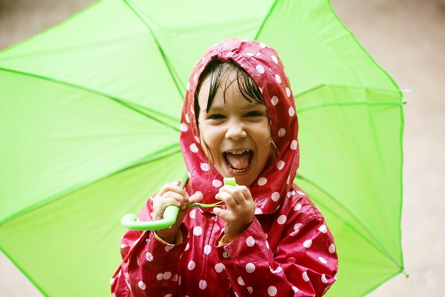 Close up of child in raincoat holding umbrella