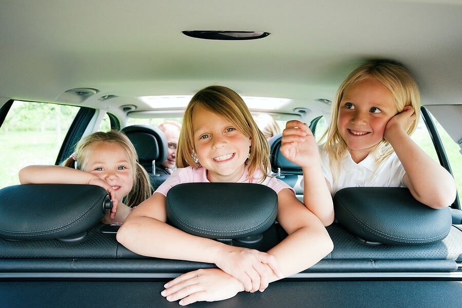Three happy children in back of car