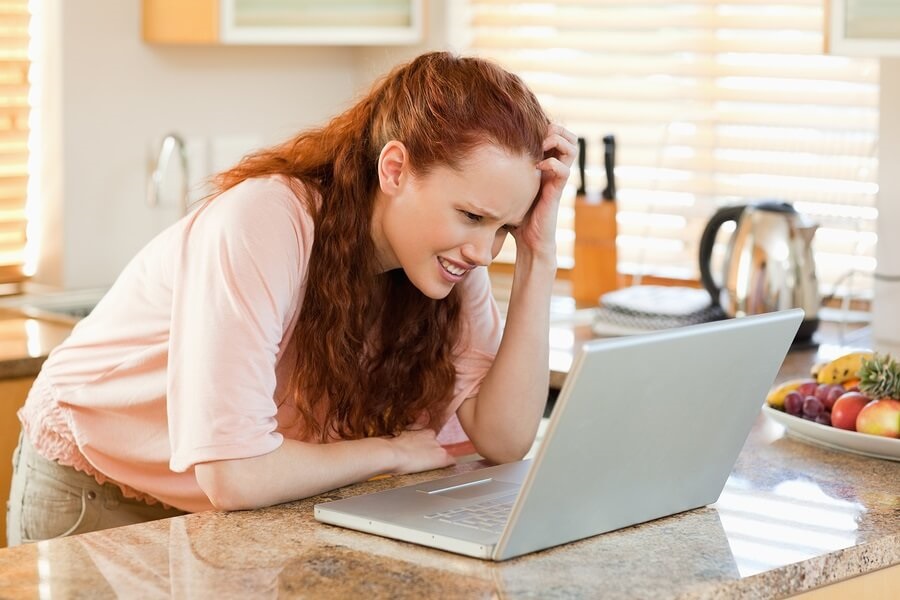 Annoyed woman on laptop in kitchen
