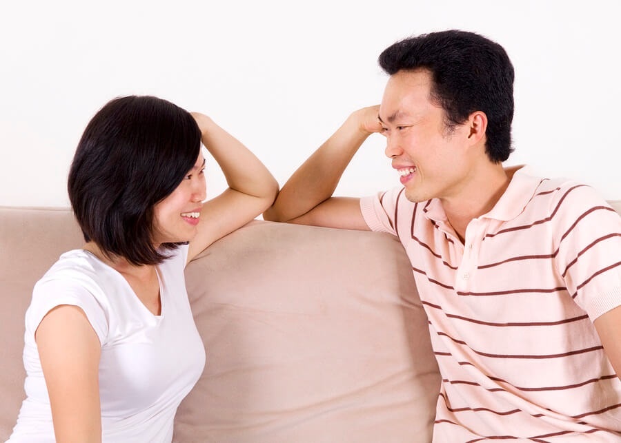 Asian couple sitting on couch talking