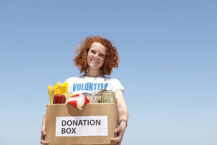 Young girl volunteer holding donation box smiling