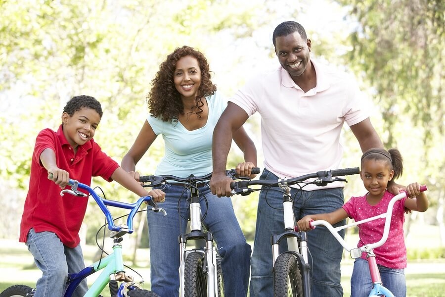 African American family riding bikes in the park