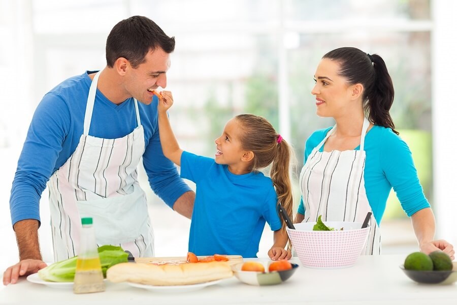 Mother, father, and daughter cooking meal in kitchen