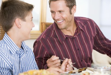 Father and son talking at dinner table