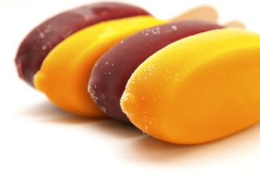 Multi-colored frozen fruit bars against white backdrop.