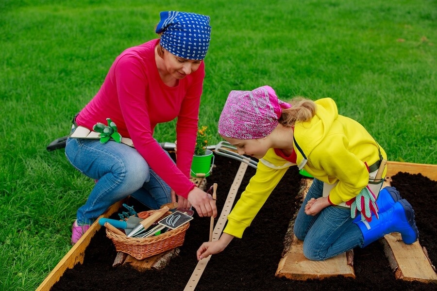 Mother and daughter planting seeds in garden