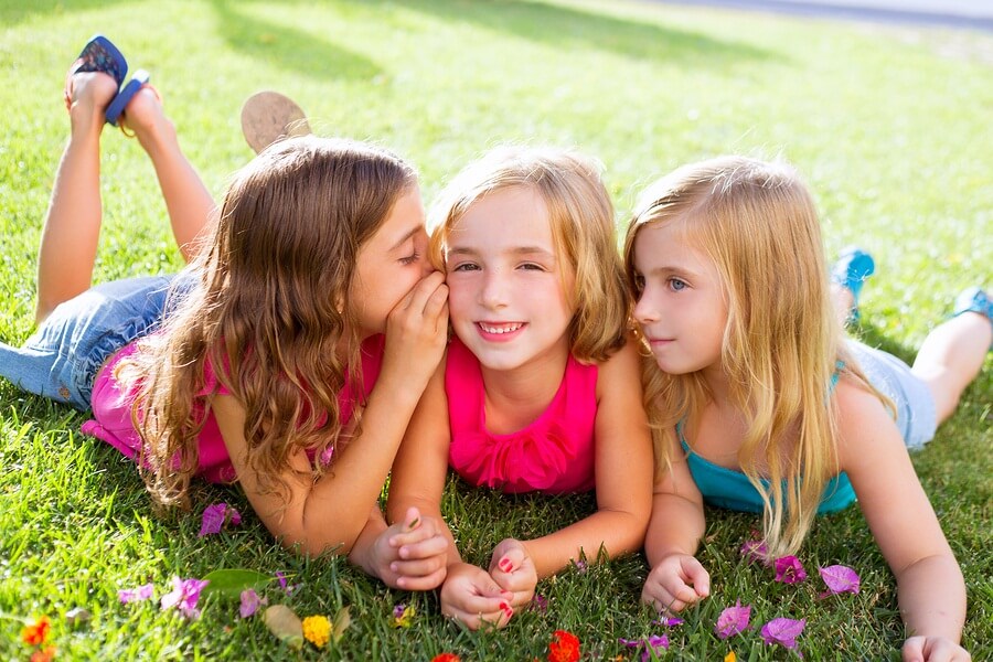 Three girls laying in grass laughing