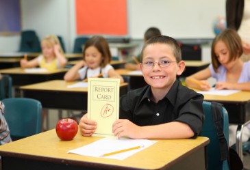 Smiling student holding up good report card