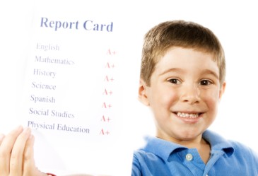 Happy boy holding up good report card