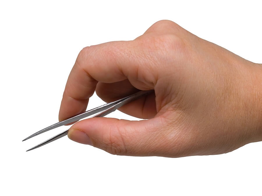 Hand holding tweezers against white background
