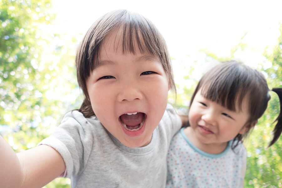 Happy Asian kids taking selfie outside