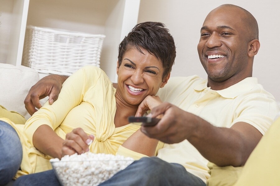 Happy couple on couch eating popcorn