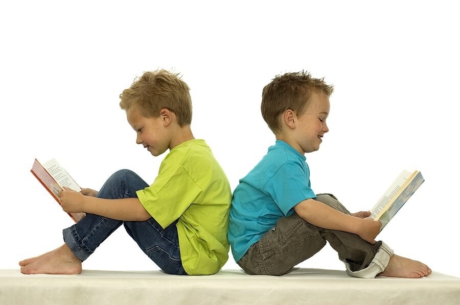 Two boys reading back to back against white background