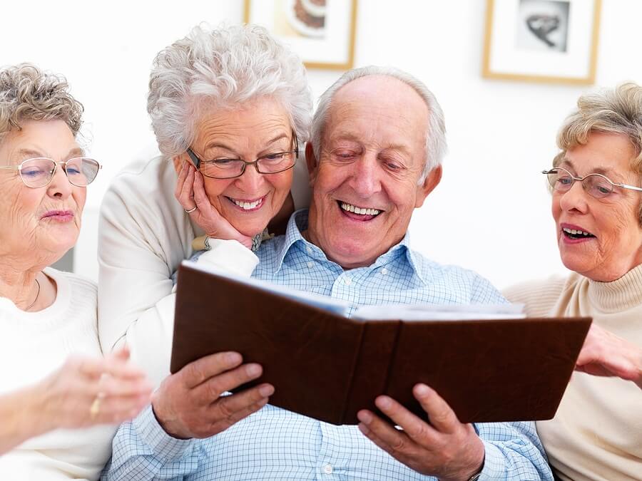 Happy elderly people looking at photo album