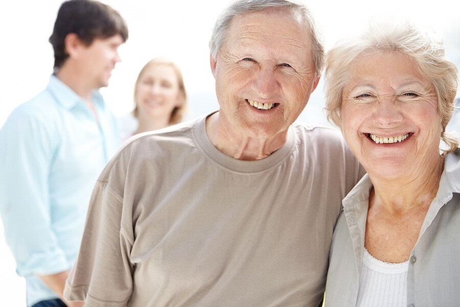 Close up of happy senior couple with grown children blurred in background