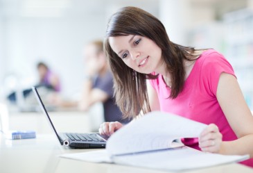 Teenage girl studying on aptop in library