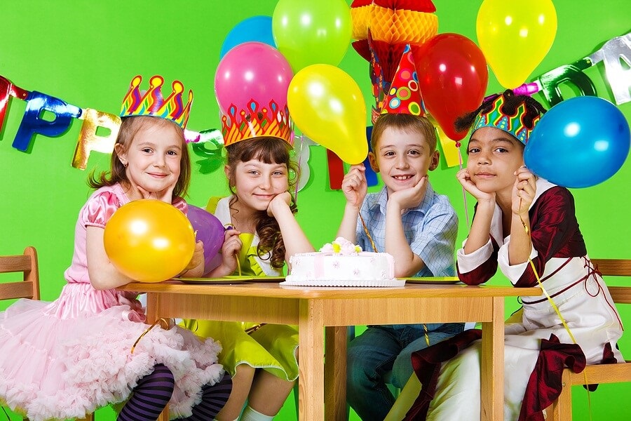 Kids sitting at table with birthday cake