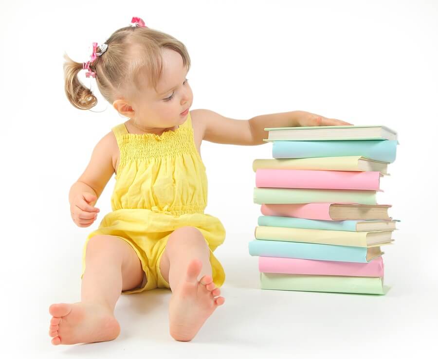 Little girl sitting next to stack of books