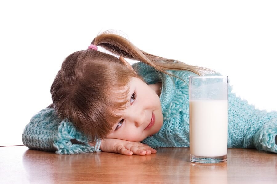 Little girl sitting at table with glass of milk