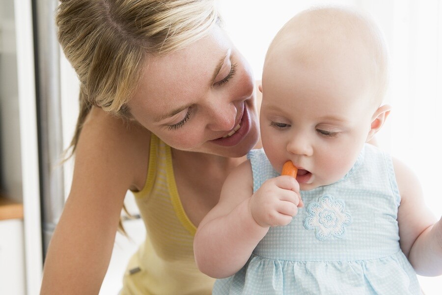 Happy mom and baby eating carrot