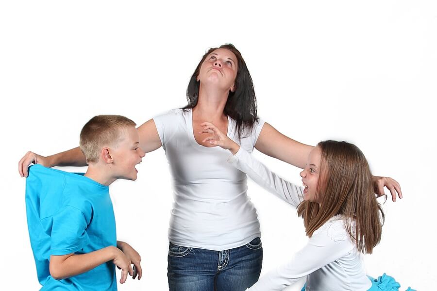 Mother holding two fighting kids back