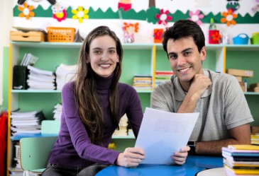 Parent and teacher sitting in classroom talking