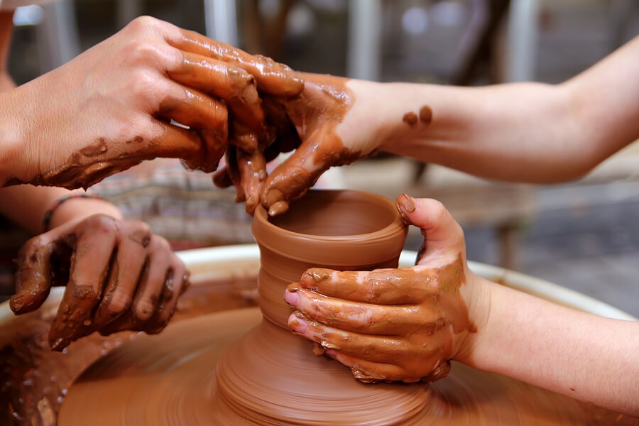 Two hands molding clay on pottery wheel