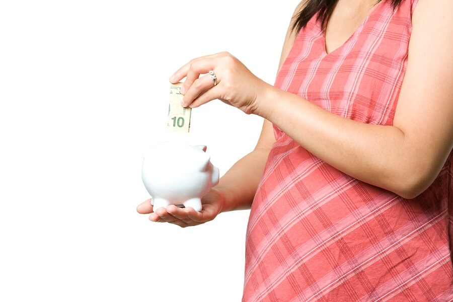 Pregnant woman putting money in piggy bank