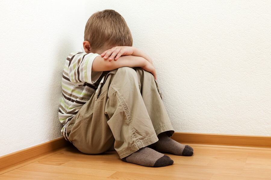 Punished child sitting in corner with head in hands