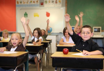 Eager students raising hands in classroom.