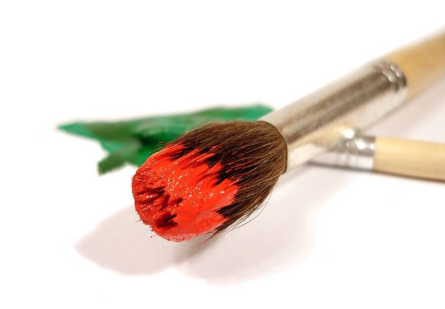Paintbrushes with red and green paint against white background