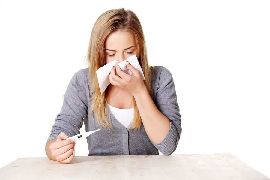 Sick teen sitting at table blowing nose