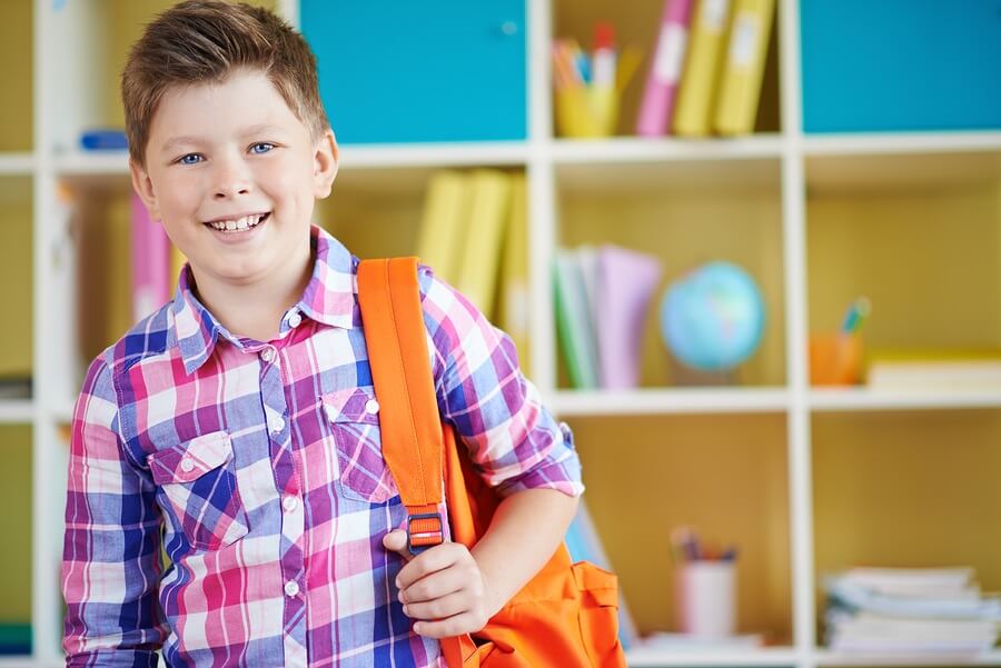 Smiling boy with backpack standing in mudroom
