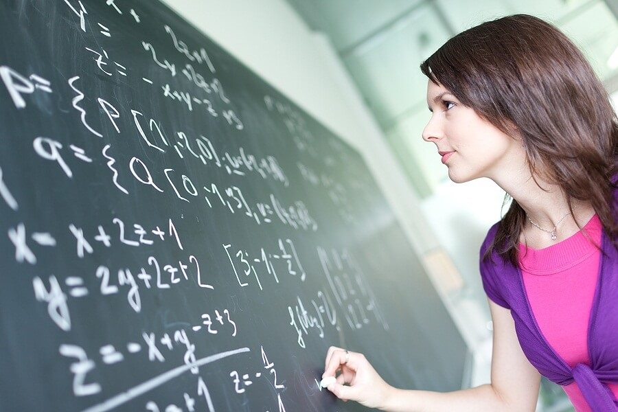 Female student writing on chalkboard
